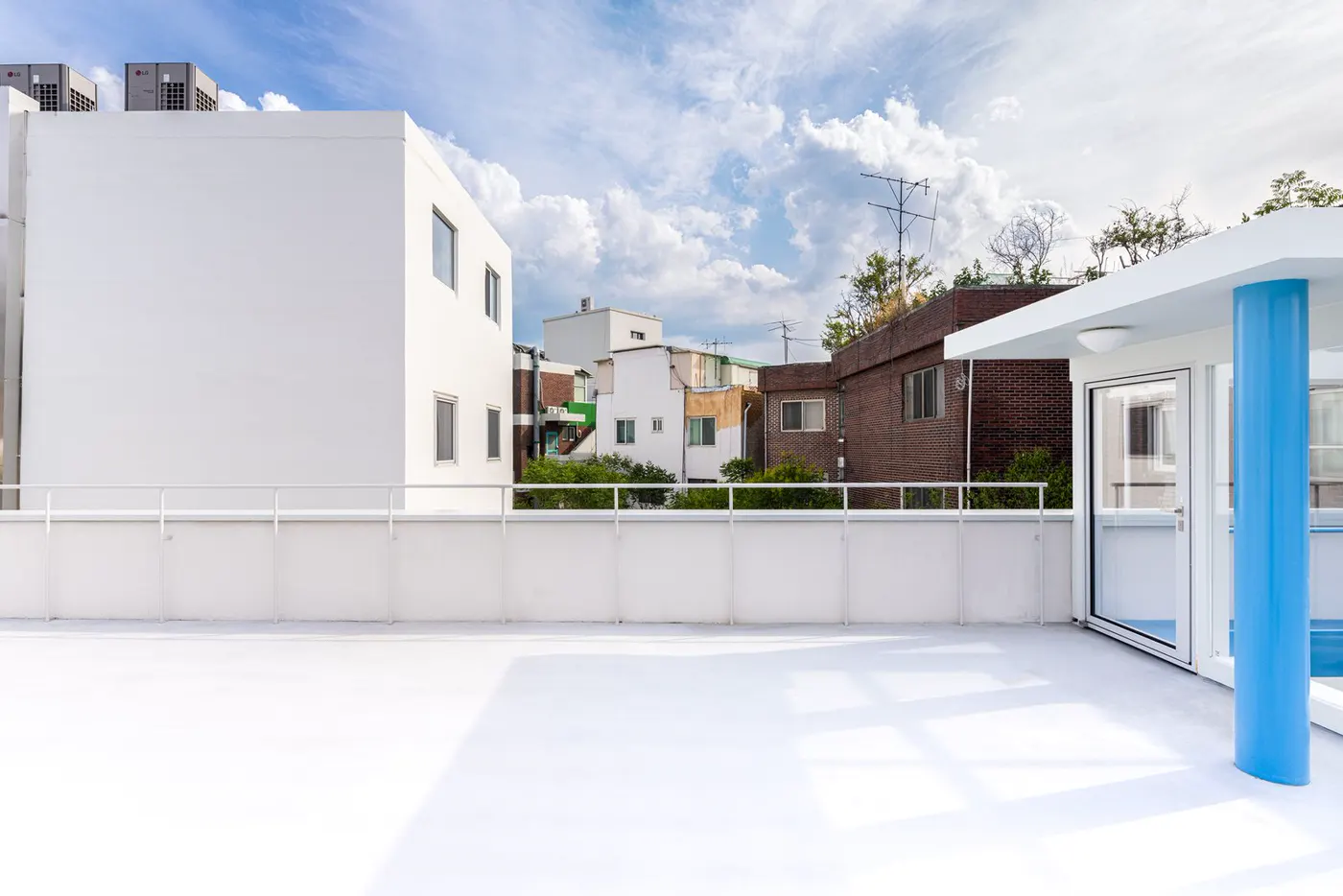 A bright white rooftop terrace with a railing under a blue sky