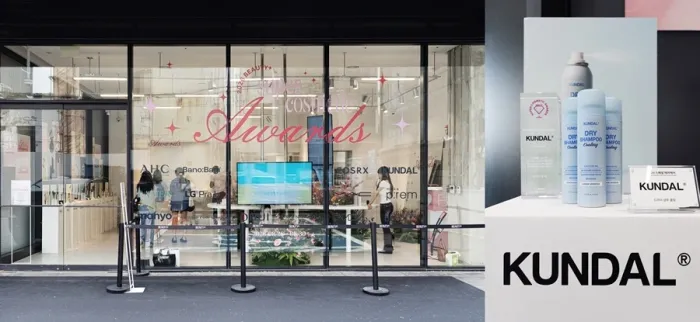 Glass storefront with award lettering and a KUNDAL product display