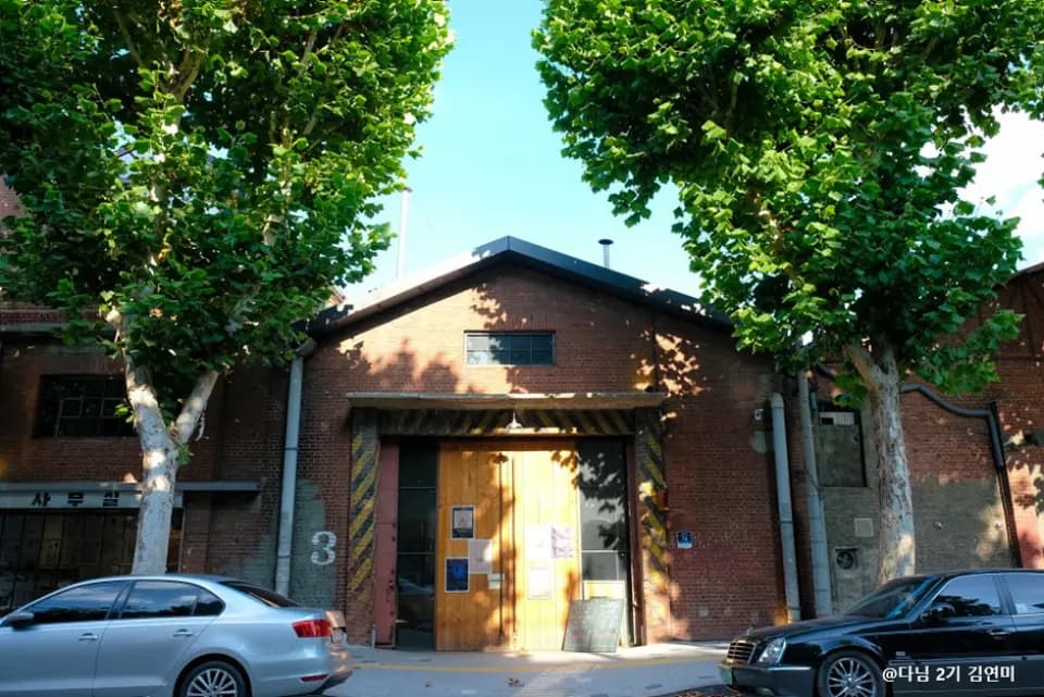 Red-brick warehouse seen between street trees