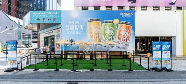 인조 잔디를 깐 야외 부스와 레몬소다 대형 광고판